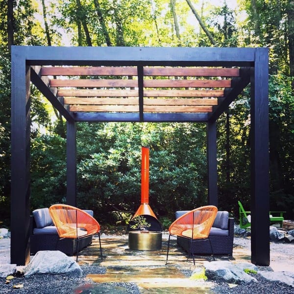 Modern steel and wood pergola with vibrant orange chairs, cozy seating, and a striking orange fireplace centerpiece.