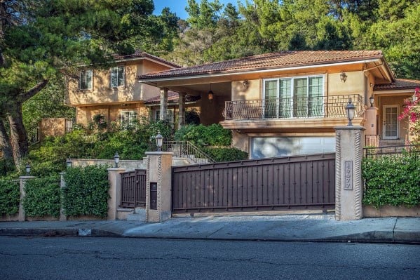 Brown steel driveway gate with vertical slats and decorative posts.