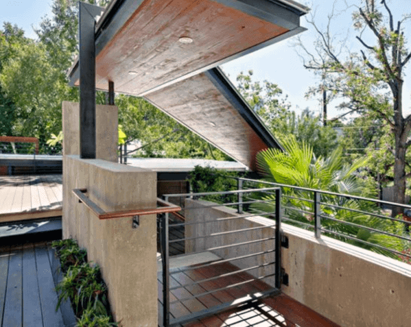 Modern rooftop terrace with greenery, wooden deck, and a gated architectural roof design