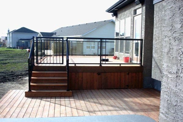 Wooden deck with stairs, black railing, and a gate overlooking the yard
