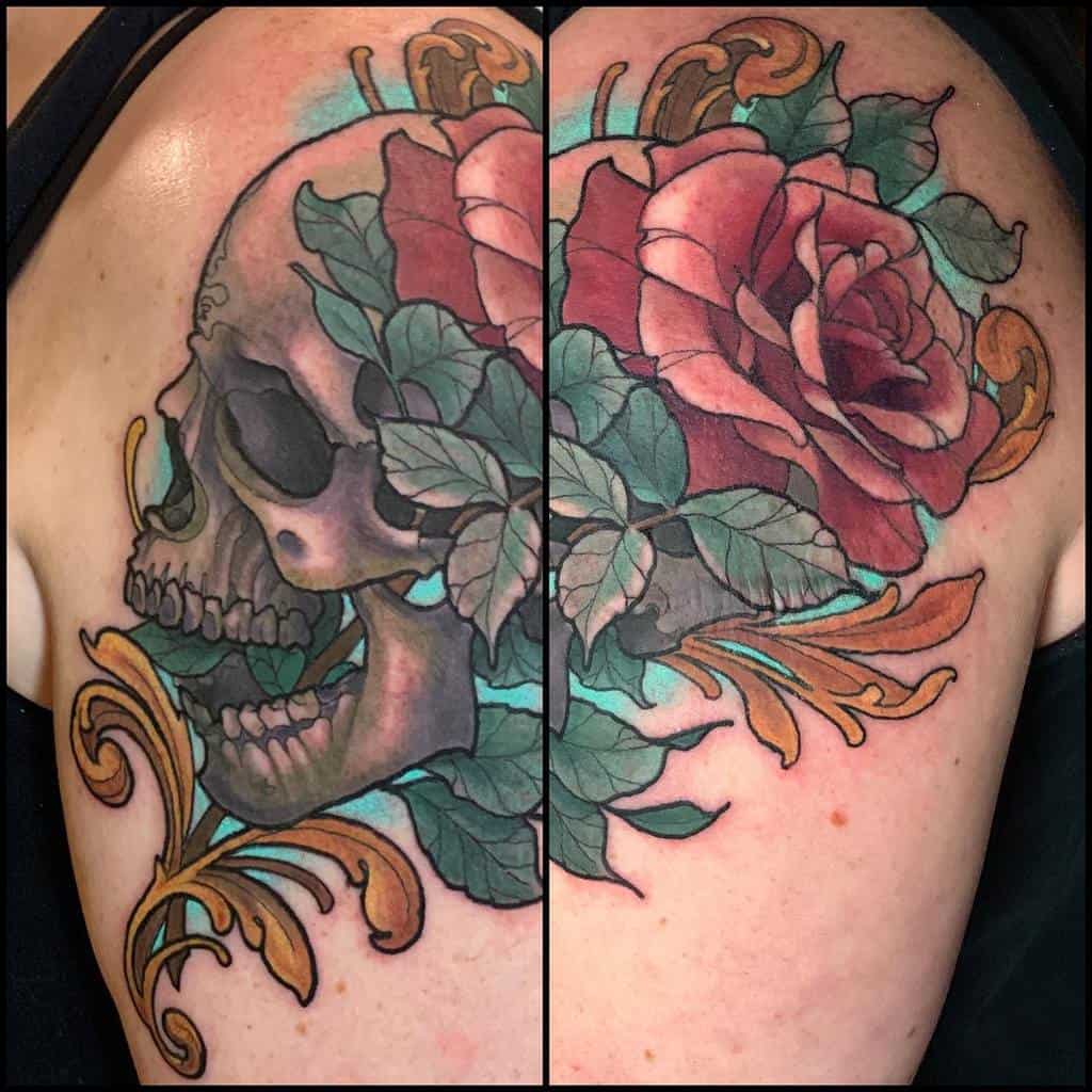 Ornate tattoo of a skull with vibrant red roses, green leaves, and golden filigree, blending realism with decorative elements on the shoulder.