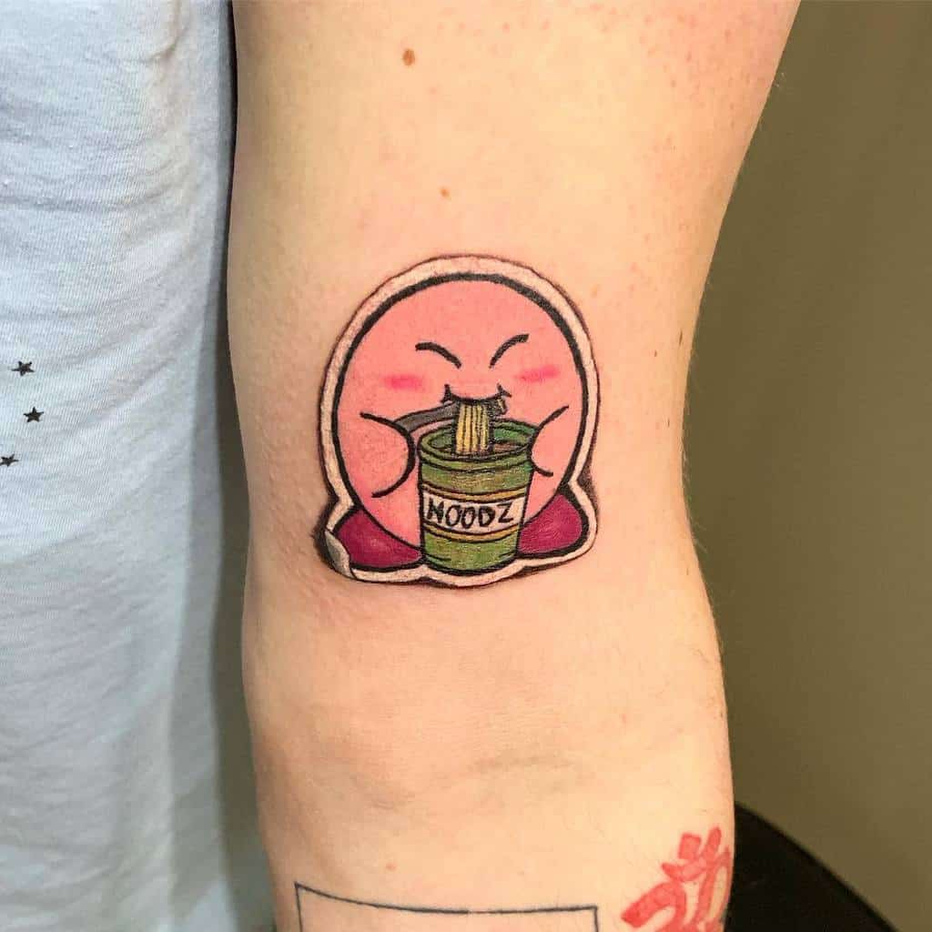 Kirby tattoo happily eating instant noodles from a cup labeled "NOODZ"