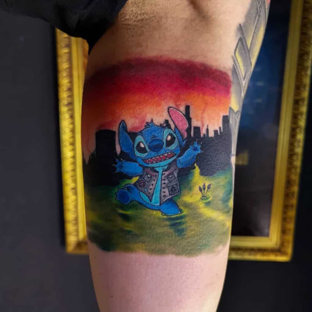 Colorful tattoo of Stitch from Lilo & Stitch wearing a vest, with a city skyline and a vibrant sunset background, on the upper arm.