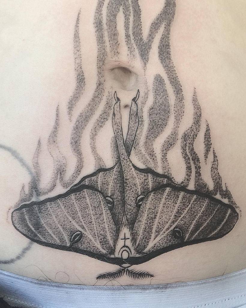 A black and grey tattoo of a Luna Moth surrounded by flames, with intricate shading
