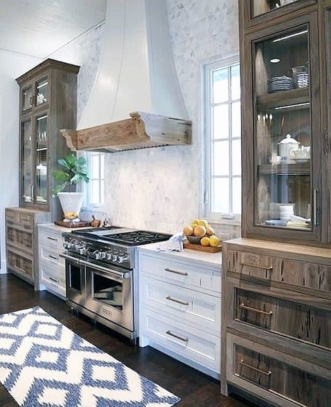 Farmhouse-style kitchen with a soft stone backsplash, rustic wood cabinetry, white range hood, and dark wood flooring