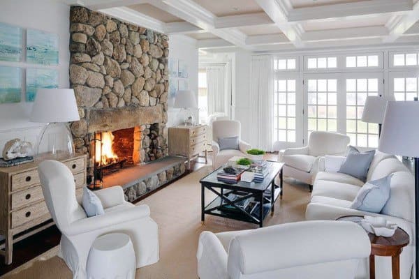 Classic living room with a rustic stone fireplace and bright, airy white furnishings.