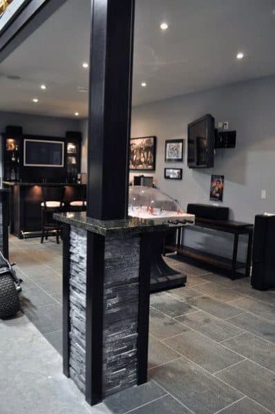 Modern basement with black stone-covered support pole and sleek bar area.