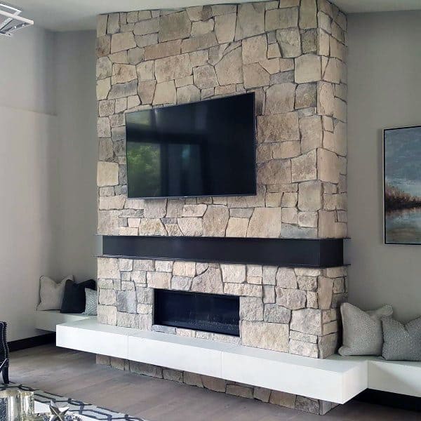 Gas fireplace with a black frame set in a stone surround, featuring a mounted TV above.