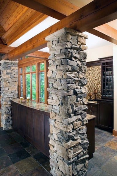 Basement with rustic stone pole covers, wood beams, and a granite countertop bar.