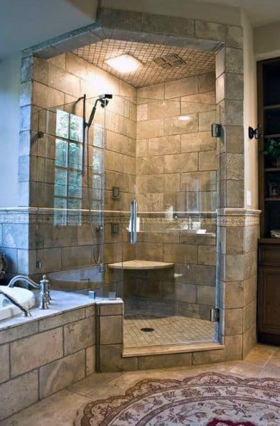 A luxurious corner shower with stone tiles and glass doors, next to a bathtub and an ornate rug on the floor