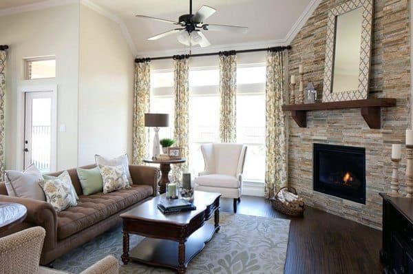Living room with stone corner fireplace, brown tufted sofa, armchair, and wood coffee table.