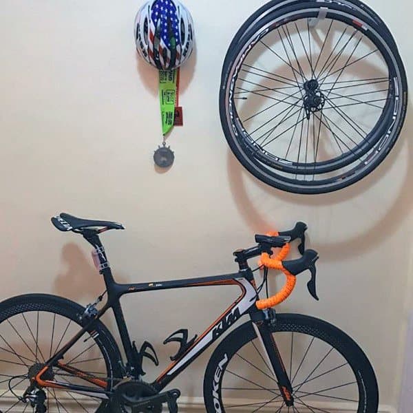 A tidy bike garage with wall-mounted wheel storage, helmet rack, and a sleek bike ready for use.