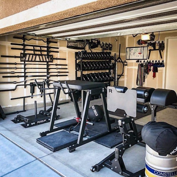 Garage gym with wall-mounted barbell storage, dumbbell rack, and versatile workout equipment.