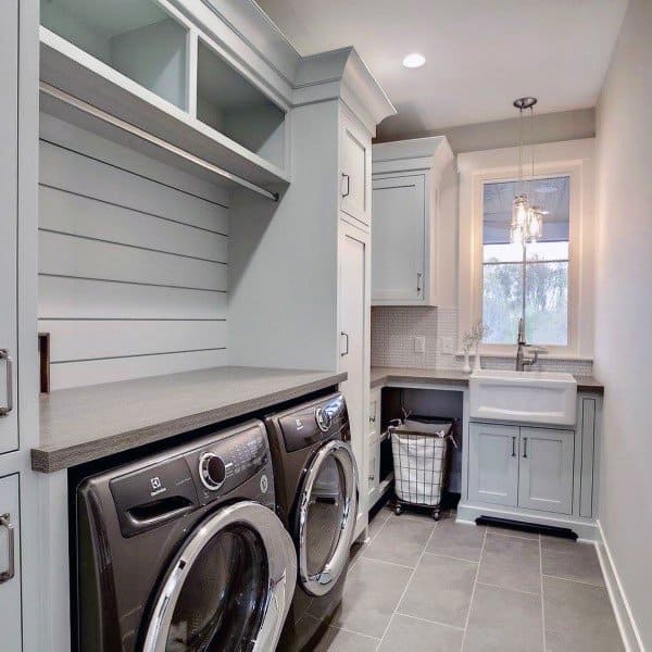 A stylish laundry room featuring light gray cabinets, shiplap wall detail, and modern appliances.