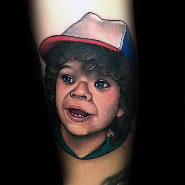 Realistic color tattoo of Dustin from Stranger Things, showcasing his signature cap, curly hair, and cheerful expression.
