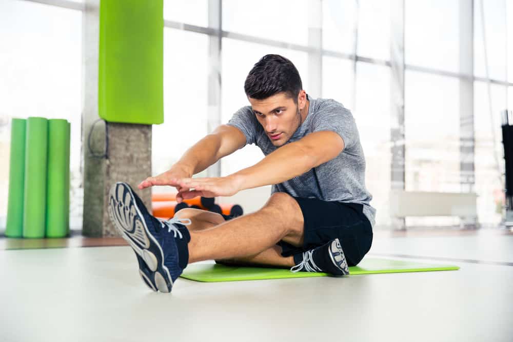man doing stretching exercise in gym