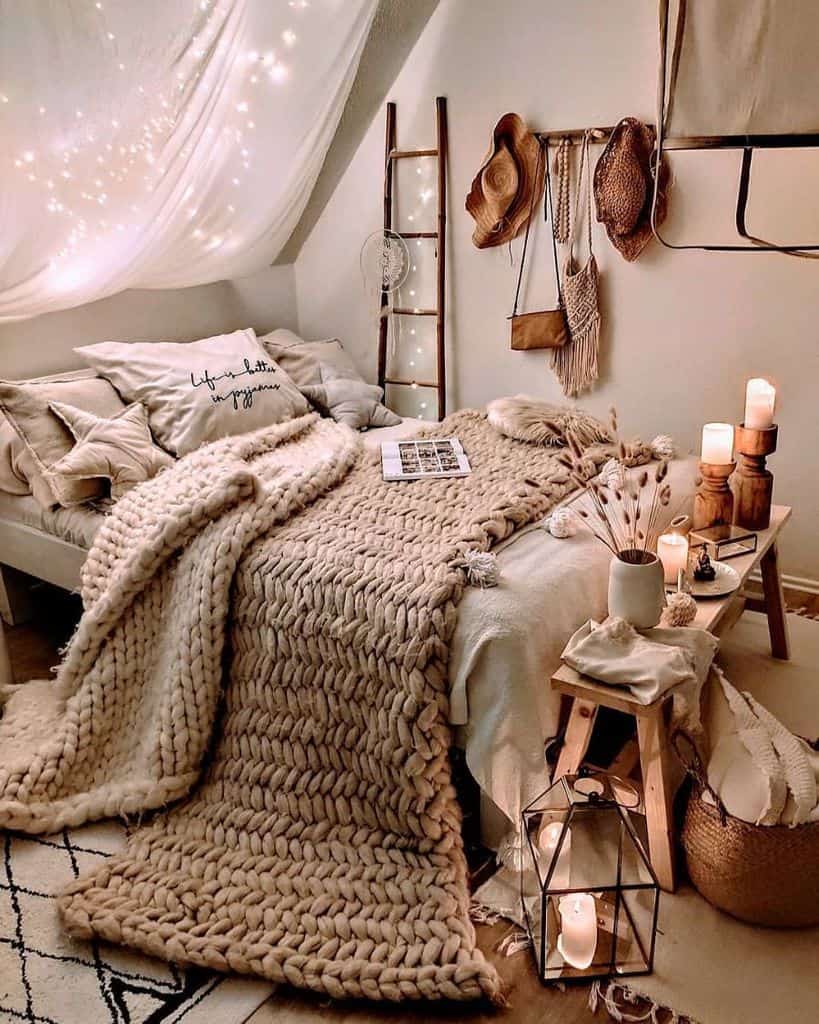 Cozy bedroom with a chunky knit blanket, candles, hats, and string lights creating a warm, inviting atmosphere