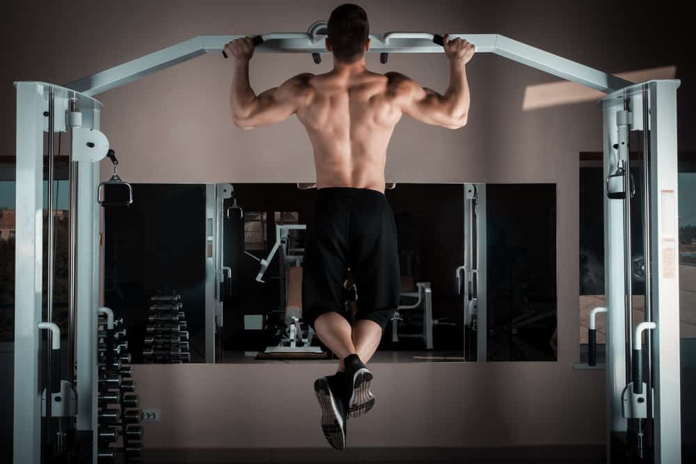 strong man doing pull ups inside gym