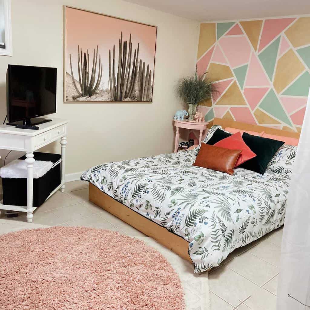 Colorful studio apartment bedroom with geometric accent wall, cactus art, and cozy bedding.