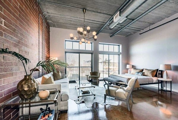 Industrial-style studio with exposed brick, modern furniture, and large windows for natural light.