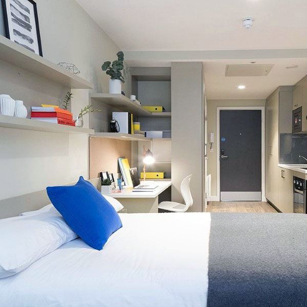 Organized studio with shelves, workspace, and compact kitchen.