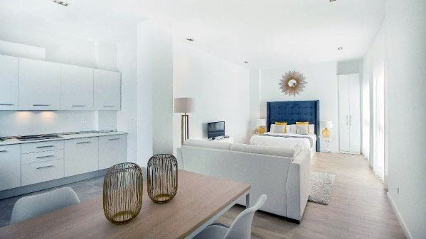 Bright studio with a dining area, cozy seating, and a stylish bed.