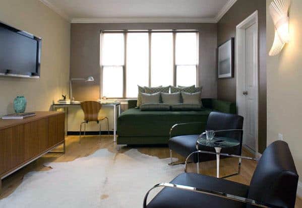 Masculine studio apartment featuring a green sofa bed, modern chairs, and a sleek workspace.