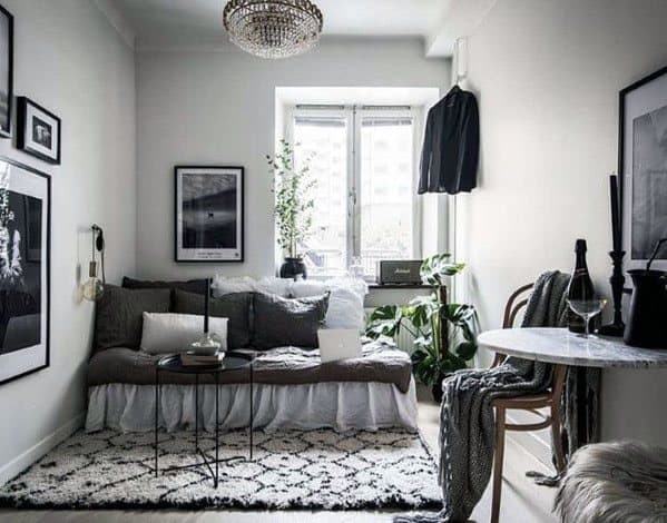 Chic studio with cozy sofa, monochrome decor, indoor plants, and a small dining table.