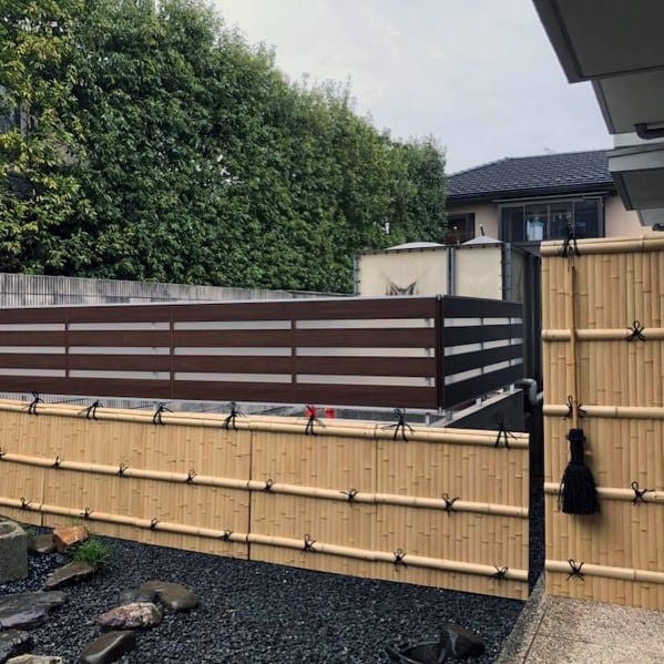 Light bamboo fence with black ties and modern wooden slats in a minimalist backyard garden.