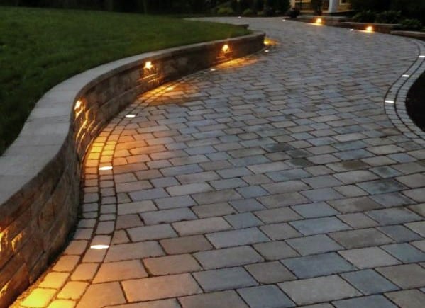 Driveway with recessed lighting embedded in the stone pavers, highlighting the curves and adding a warm, inviting glow at night
