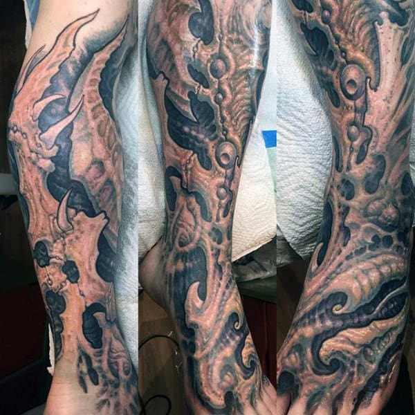 A forearm tattoo with a biomechanical design featuring intricate gears, pipes, and organic shapes