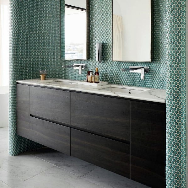 Luxury bathroom with dark wood double vanity, marble countertop, and green hexagonal tile backsplash.