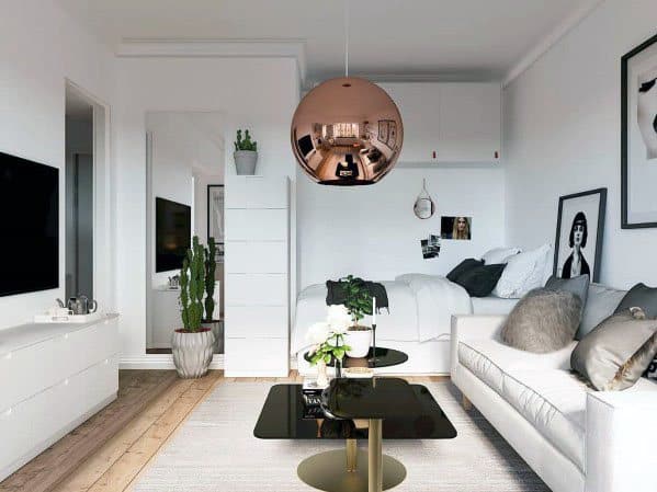 Bright studio with white decor, rose gold pendant light, cozy sofa, and modern accents.