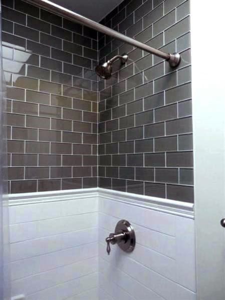 Shower with dark gray subway tiles on top, white tiles on bottom, and silver fixtures.