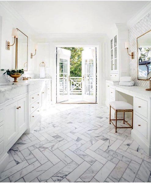 Bright bathroom with white marble flooring, open French doors leading outside
