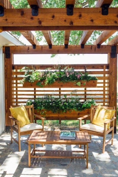 Wooden pergola with cozy seating and a vertical garden wall.