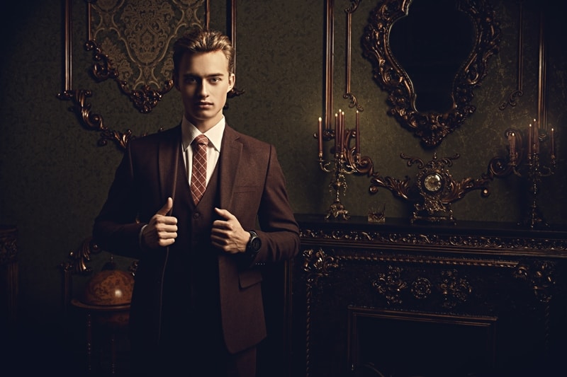 A young man in a brown suit and red tie