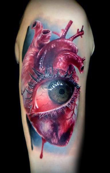Tattoo of a realistic human heart with a detailed eye in the center, complete with eyelashes, on a person's arm