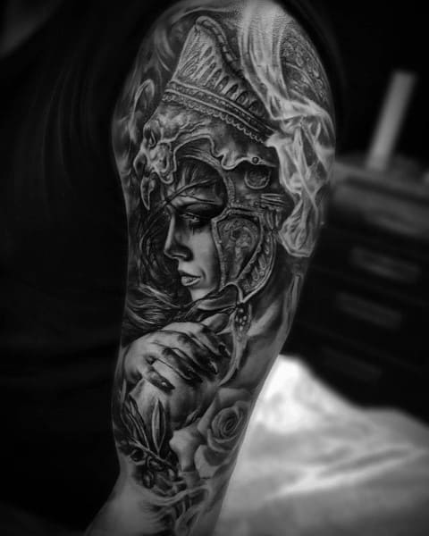 Black and grey realism tattoo sleeve of Athena with detailed helmet, intense gaze, olive branch, and soft shading across the upper arm