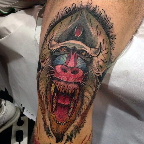 Neo-traditional baboon tattoo with bold colors, intense shading, and a mystical third eye, creating a fierce and dynamic thigh design.