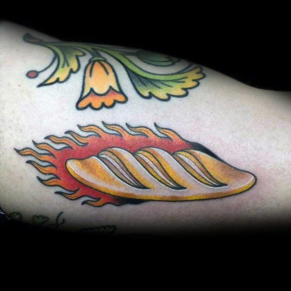 Colorful tattoo of a golden loaf of bread surrounded by bright orange flames, creating a bold and dynamic design with a traditional tattoo style.