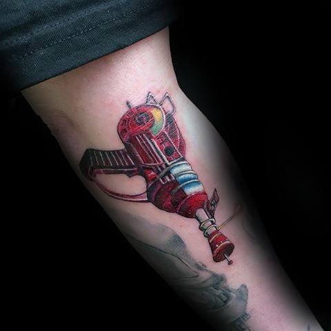 Detailed Call of Duty Ray Gun tattoo on the forearm, featuring vibrant red tones, bold outlines, and a futuristic energy weapon design.