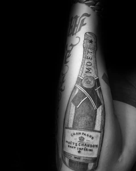 Black and white tattoo of a Moët & Chandon champagne bottle on an arm.
