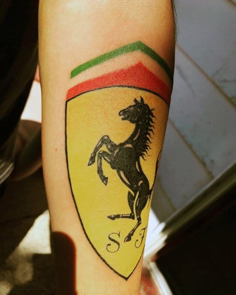 Bright Ferrari shield tattoo featuring iconic black horse and Italian flag colors, symbolizing passion for racing, inked on man's forearm.