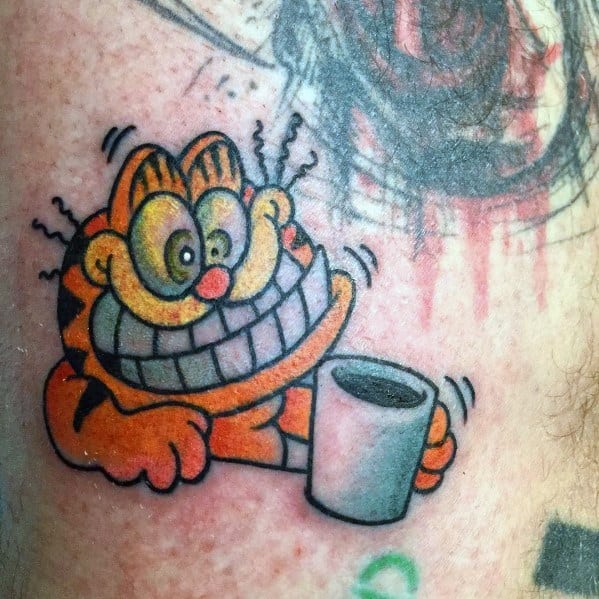Garfield tattoo with an exaggerated wide grin, holding a coffee cup—vibrant and fun design capturing caffeine-fueled energy.