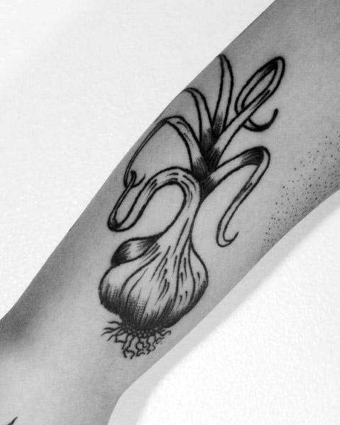 Black and grey garlic tattoo with flowing, curved stems and fine shading, creating a bold and organic botanical design on the forearm.