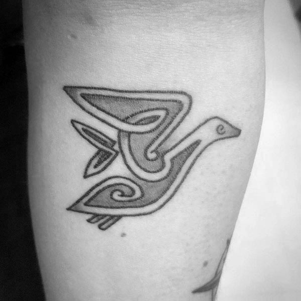 Minimalist black ink tattoo of a stylized goose in flight, featuring bold lines and geometric patterns, inked on the forearm.