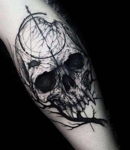 Black and grey tattoo featuring a cracked skull with dark hollow eyes, surrounded by twisted branches and fine line details for a gothic look.