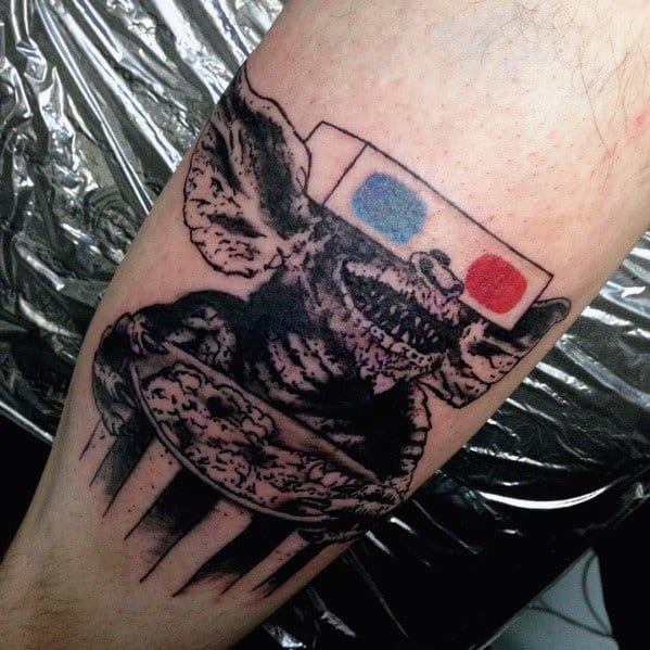 Black and gray Gremlin tattoo with 3D glasses and a bucket of popcorn, blending horror and nostalgia in a bold, sketch-style design.