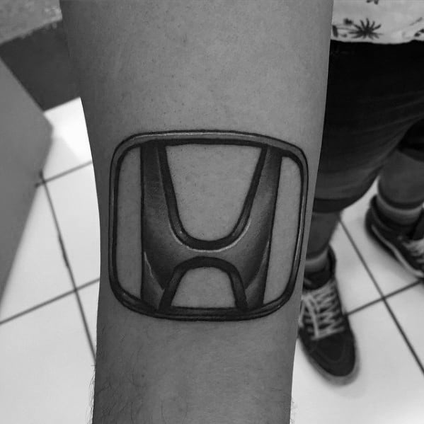 Realistic Honda logo tattoo on a man's forearm, featuring bold shading and a three-dimensional effect for a striking and detailed design.